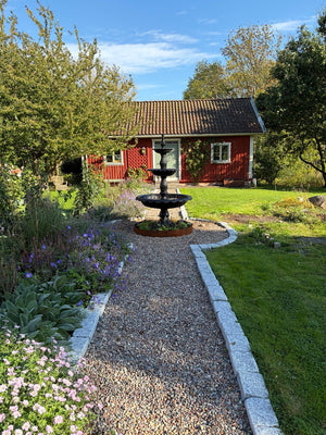 Fontän Edward vid grusgång och trädgård