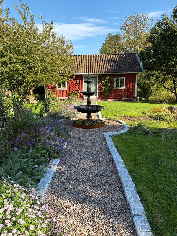 Fontän Edward vid grusgång och trädgård